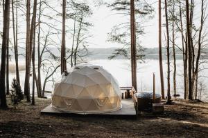 a tent sitting on a dock next to a body of water at Asalnai Campsite in Ignalina