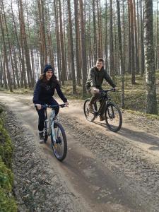 un homme et une femme à bord de vélos sur un chemin de terre dans l'établissement Asalnai Campsite, à Ignalina