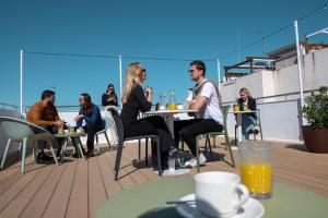 a group of people sitting at tables on a balcony at Aila II Hotel Boutique by SingularStays - Digital Access in Burjassot