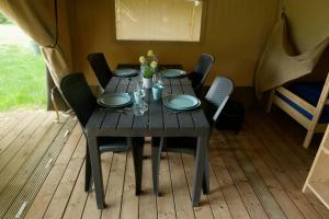 uma mesa de madeira com cadeiras e pratos em Safaritent op groen en kindvriendelijk park op de Veluwe em Epe