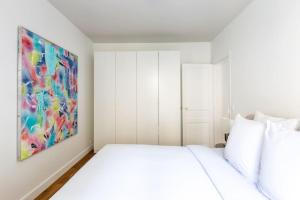 un dormitorio blanco con una pintura en la pared en Invalides - Rénové - Luxe, en París