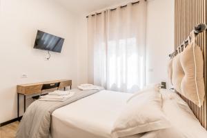 - une chambre blanche avec un lit et une télévision dans l'établissement Casa Roma B&B, à Rome