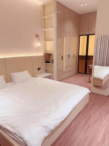 um quarto com uma grande cama branca e uma cadeira em Malloire House Hue em Hue