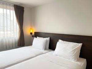 2 Betten in einem Hotelzimmer mit weißer Bettwäsche und Kissen in der Unterkunft Pas Cher Hotel de Bangkok in Bangkok