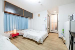 1 dormitorio con 2 camas y mesa roja en Uhome Tabata Apartment en Tokio