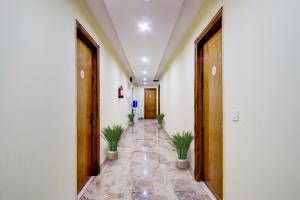 a hallway with two potted plants in a building at Super Capital O Hotel Crestwood Inn in Dehradun