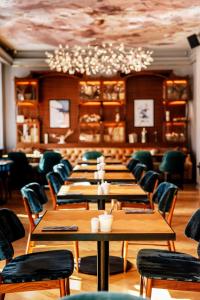 a dining room with tables and chairs and a chandelier at Grand Poet Hotel and SPA by Semarah in Rīga