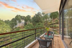 a balcony with two chairs and a table with a view at Mountain Crest Kasauli I 2 Bhk Service Apartment I Kasauli in Kasauli