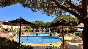 ein Pool mit Sonnenschirmen und Menschen in einem Resort in der Unterkunft Bicos J by Check-in Portugal in Albufeira