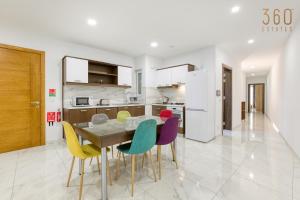 eine Küche mit einem Holztisch und bunten Stühlen in der Unterkunft Beautiful 3BR Apt with Panoramic Terrace in Qawra by 360 Estates in St Paul's Bay