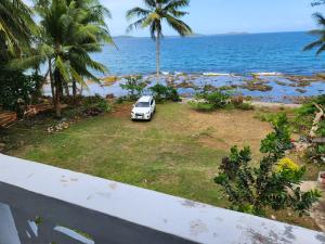 une voiture blanche garée sur l'herbe près de l'océan dans l'établissement Twin Island Beach House, à Hinunangan
