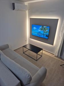 a living room with a couch and a tv on a wall at Lux apartmani Anastasija in Sutomore