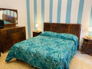 een slaapkamer met een bed met een blauw dekbed en een televisie bij Maremma Nel Tufo Centro in Pitigliano