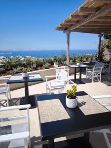 un patio con tavoli, sedie e vista sull'oceano di Kipos Villas & Suites a Mykonos Città