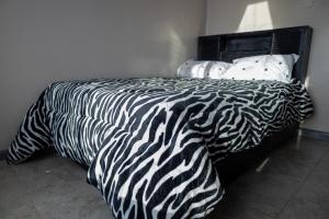 ein Bett mit Zebra-Abdruck in einem weißen Zimmer mit einem Bettröckchen-Brustspeck in der Unterkunft Cherry Home Stays KE in Nairobi