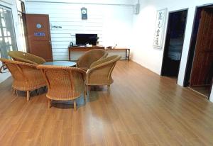 Habitación con sillas de mimbre, mesa y TV. en OYO 90971 Pollock Homestay en Sungai Lembing
