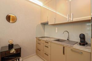 a kitchen with white cabinets and a sink at Grand Suites Promenade in Budapest +114 photos