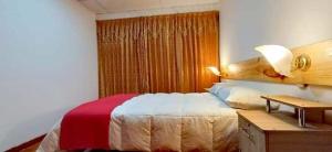 a bedroom with a bed and a desk with a lamp at Eden Lodge in Cabanaconde