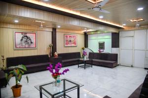 a waiting room with couches and tables and flowers at Hotel Uday Palace in Indore