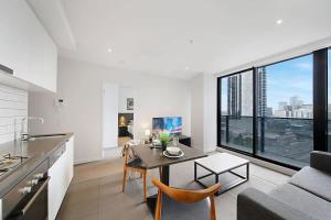 uma cozinha e sala de estar com uma mesa e um sofá em A Stylish & Comfy 2BR Apt City Views in Southbank em Melbourne