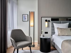 ein Schlafzimmer mit einem Bett, einem Stuhl und einer Lampe in der Unterkunft Leonardo Royal Hotel Warsaw in Warschau