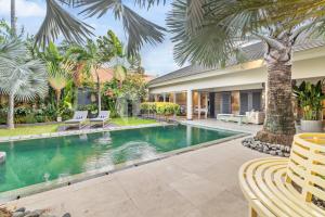 una imagen de una piscina en una casa con palmeras en Atelier by Kozystay - Artistic Villa in Sanur, en Sanur