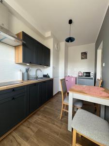 eine Küche mit schwarzen Schränken und einem Tisch mit Stühlen in der Unterkunft Wieczorek Apartment in Kudowa-Zdrój