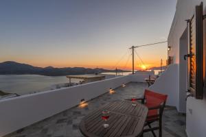 a table and chairs on a balcony with the sunset at Noula House & Studios in Plaka Milou