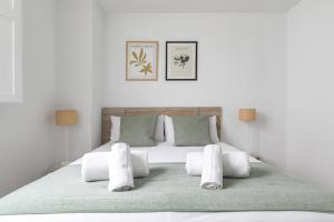 1 dormitorio con 1 cama blanca grande con almohadas blancas en Piso luminoso con balcones frente Parque Retiro en Madrid