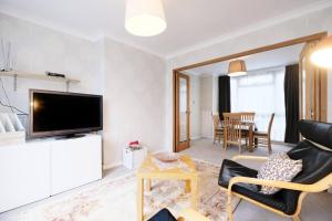 a living room with a television and a table with chairs at Pass the Keys - Beautiful Flat with balcony in Swiss Cottage, London in London