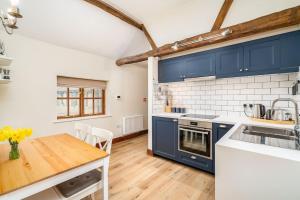 a kitchen with blue cabinets and a wooden table at Well Cottage - Compact & Cosy! in Buckinghamshire