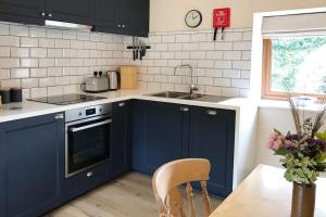 a kitchen with blue cabinets and a sink and a table at Well Cottage - Compact & Cosy! in Buckinghamshire