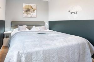 a bedroom with a large bed with a white comforter at Appartement MEERzeit in Wenningstedt