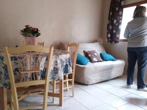 a woman standing in a room with a table and a couch at Gite de la melisse in Lairière