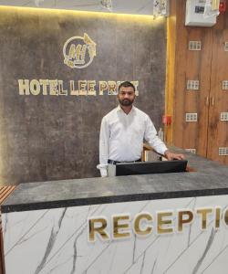 a man standing in front of a hotel tieppe counter at Hotel Lee Pride in Anand