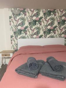 due asciugamani su un letto con coperta rosa di B&B Occhiolà a Grammichele