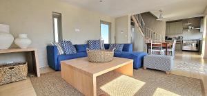 a living room with a blue couch and a table at Salt Water House in Paternoster