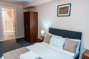 a bedroom with a large bed and a wooden cabinet at Entire 2 Bedroom and 2 Bathroom Apartment in Manchester City -Free underground Parking in Manchester