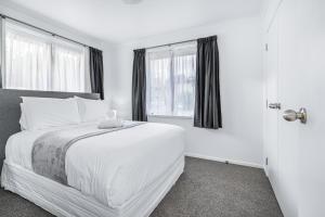 1 dormitorio blanco con 1 cama y 2 ventanas en Park Scenery, Proximity and Value - By KOSH BNB, en Hamilton