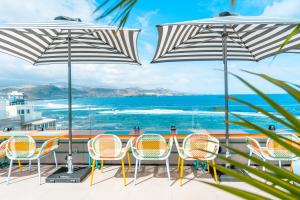 un patio con sillas y sombrillas con vistas al océano en Occidental Las Canteras, en Las Palmas de Gran Canaria