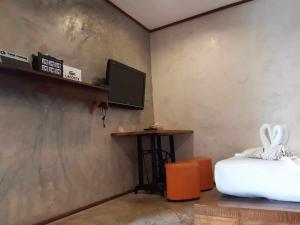 a room with a bed and a tv on a wall at BaanChompooAmphawa in Amphawa