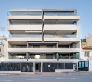 un edificio blanco alto con una valla delante en Speiō Luxury House, en Heraclión