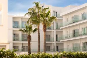 two palm trees in front of a building at Hotel Capricho in Cala Ratjada