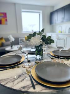 a table with plates and glasses and a vase of flowers at Luxury Norwich City Centre Apartment - Free Parking in Norwich