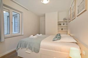 a white bedroom with a bed and a window at Knokke La Douce - Cozy apartment with side sea-view at only 50 meters from beach in Knokke-Heist