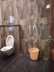 a bathroom with a toilet and a trash can at Iris Comfort Inn in Chennai