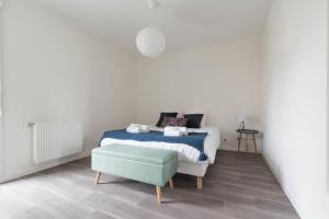 ein weißes Schlafzimmer mit einem Bett und einer grünen Ottomane in der Unterkunft NATHAN - Appartement proche gare arrivée 2424 in Le Mans