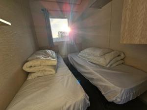 two beds in a small room with a window at Caravan LEANNE in Meliden