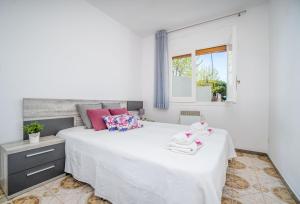 エンプリアブラバにあるBasic Comfort Apartment Port Emporda 0195の白いベッドルーム(ピンクの枕が付いた大きな白いベッド付)