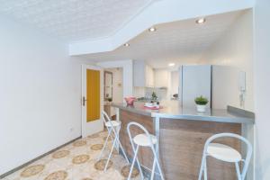 エンプリアブラバにあるBasic Comfort Apartment Port Emporda 0195の白い壁のキッチン、カウンター(スツール付)